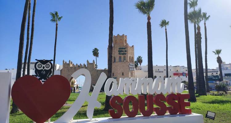 Panneau de Hammam Sousse avec palmiers et bâtiments.