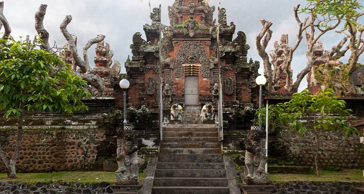 Entrée en pierre ornée avec des sculptures complexes dans un temple balinais.