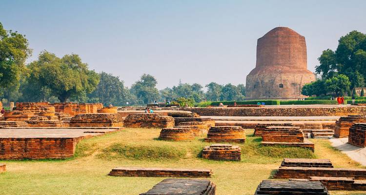 Ruinas de ladrillo y piedra de Sarnath con la enorme Estupa Dhamek de fondo.