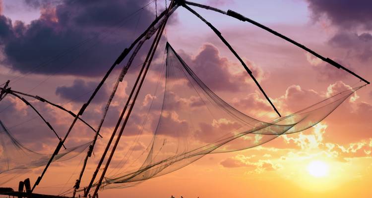 Silhouette von Fischernetzen vor einem Sonnenuntergangshimmel, mit Wolken und untergehender Sonne.