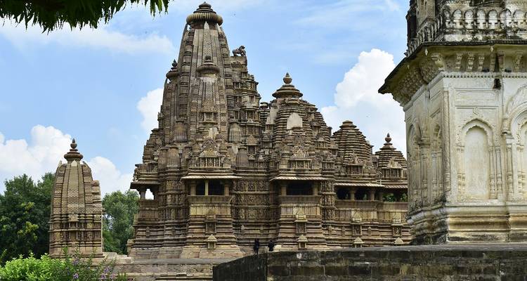 Templos de arenisca tallados con intrincados detalles en Khajuraho destacándose contra un cielo azul.