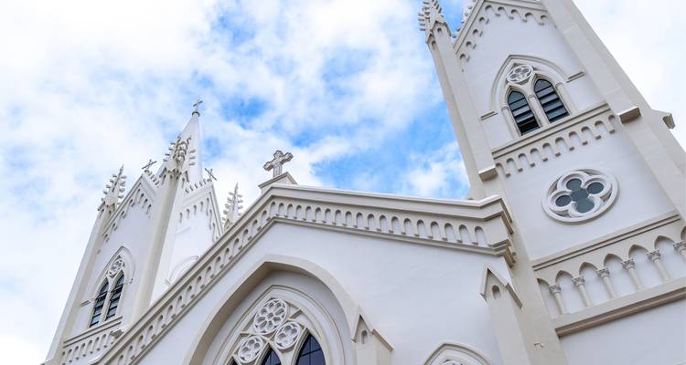 Façade d'église de style gothique blanc contre un ciel bleu.