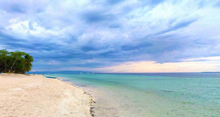 Malerischer Strand mit blauem Wasser und bewölktem Himmel.