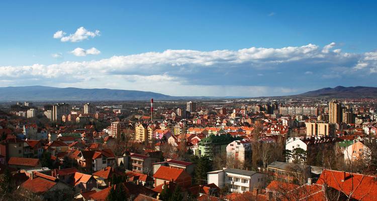 Vue aérienne d'une ville avec de nombreux bâtiments et des montagnes en arrière-plan.