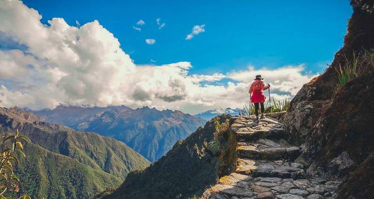 Personne faisant de la randonnée sur un sentier de montagne avec vues panoramiques.