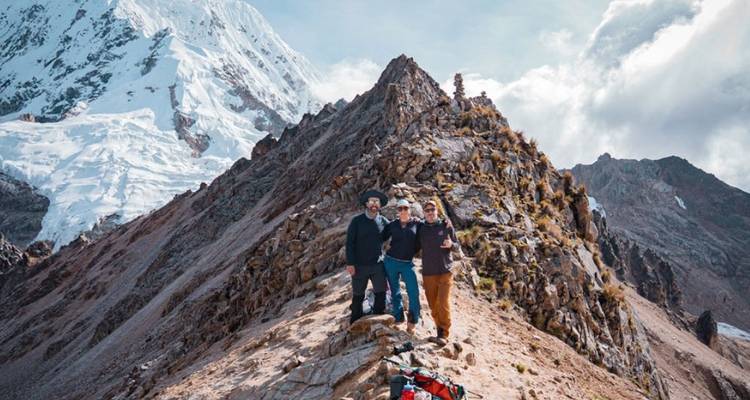 Groupe de randonneurs sur une crête de montagne avec des sommets enneigés.