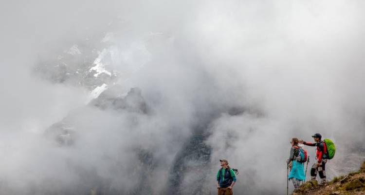 Des gens sur un sentier de montagne brumeux.