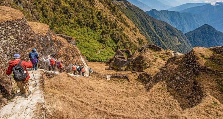 Randonneurs marchant à travers des ruines antiques avec un vaste paysage.
