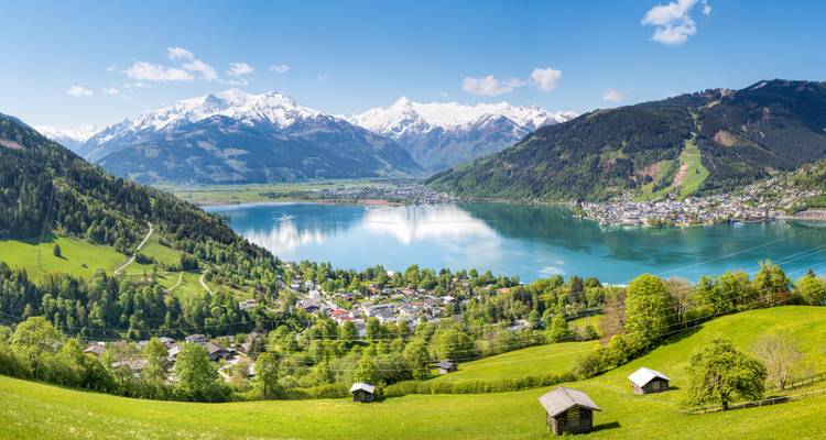 Vue panoramique d'un lac serein entouré de montagnes et d'une petite ville.
