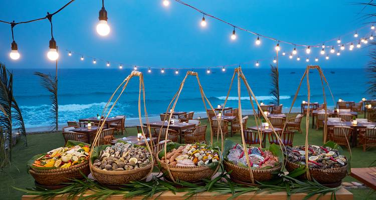 Repas en bord de mer avec paniers de fruits de mer et éclairage d'ambiance.