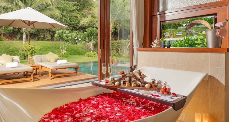 Baignoire de luxe remplie de pétales de rose et aménagée avec vue.