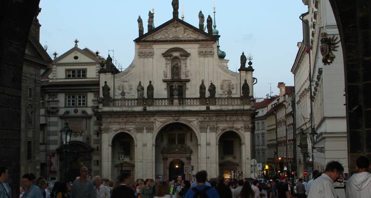 Historisch gebouw met een boogvormige gevel in een stedelijke omgeving, vol met mensen.