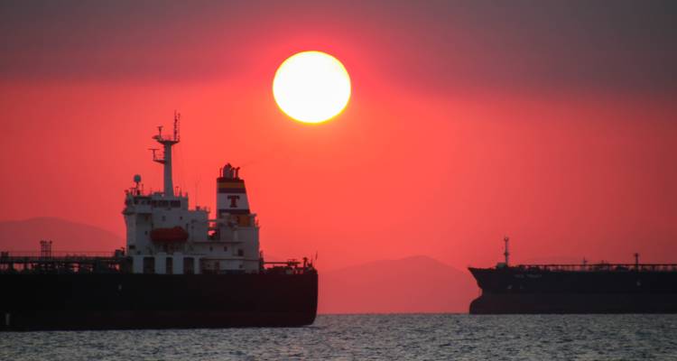 Navires de fret en mer au coucher du soleil avec un grand soleil brillant.