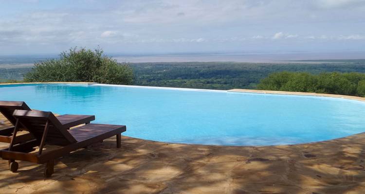 Piscina infinita con tumbonas con vista a un paisaje exuberante.