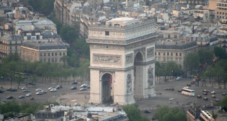 El Arco del Triunfo rodeado de edificios y una rotonda de tráfico.
