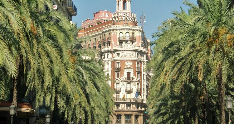 Edificio histórico de banco rodeado de palmeras.