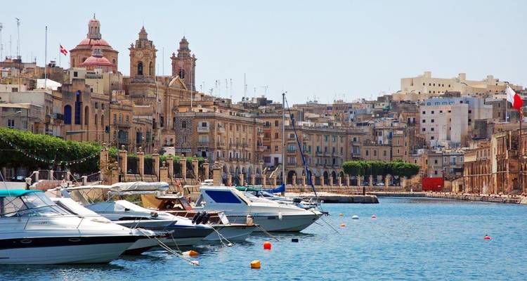 Waterkantgezicht met boten en historische gebouwen.