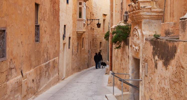 Smalle steeg in een historische stad met twee mensen die lopen.