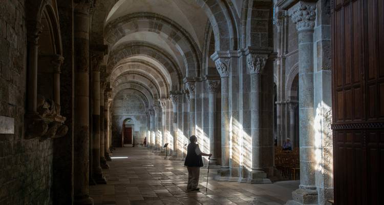 Interior de un edificio histórico con arcos y luz que se filtra hacia adentro.