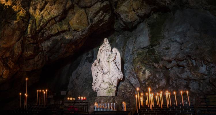 Estatua dentro de una cueva con velas.