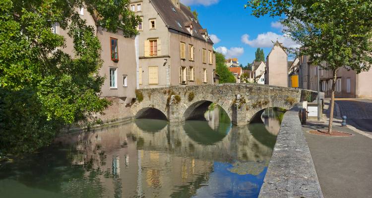 Puente de piedra sobre un río tranquilo en un pueblo.