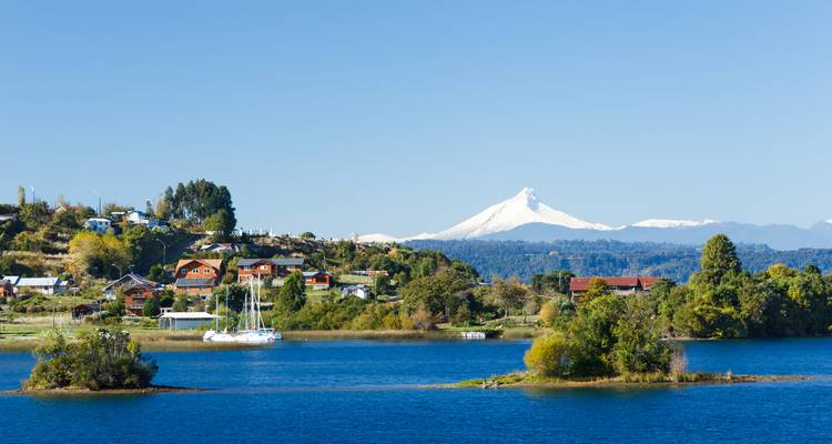 Schilderachtig uitzicht op meer met besneeuwde berg en huizen.
