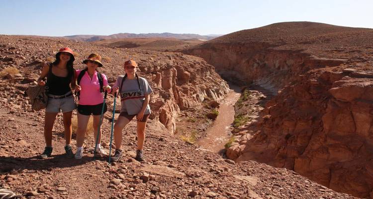 Drie mensen poseren bij een uitzichtpunt van een canyon.