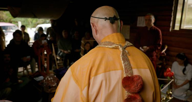 Monje conduciendo una ceremonia en una habitación con personas.