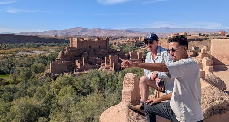 Dos hombres sentados señalando hacia las ruinas de la fortaleza.