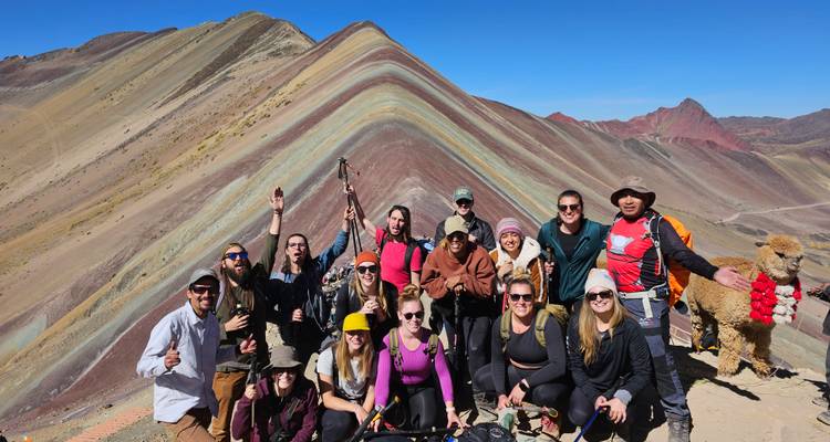 Grupo de excursionistas en la Montaña Arcoíris con paisaje de rayas coloridas.