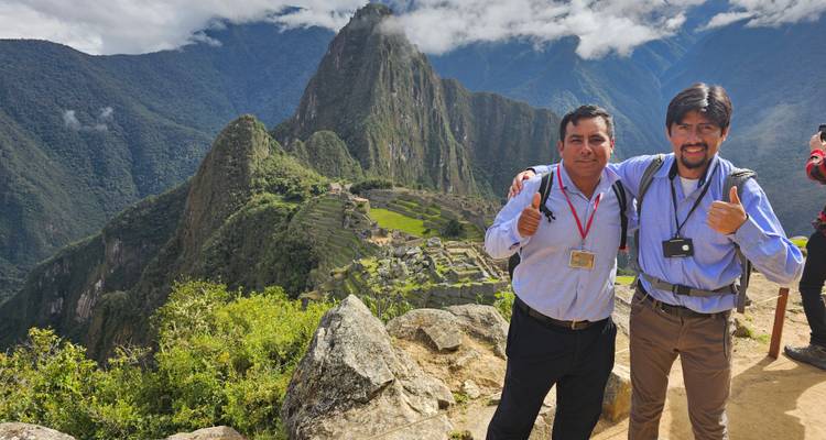 Dos hombres dando pulgares arriba con Machu Picchu en el fondo.