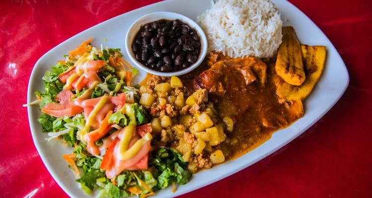 Plato de comida tradicional con arroz, frijoles, carne y ensalada.