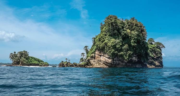 Islotes rocosos aislados cubiertos de exuberante vegetación en medio del océano.