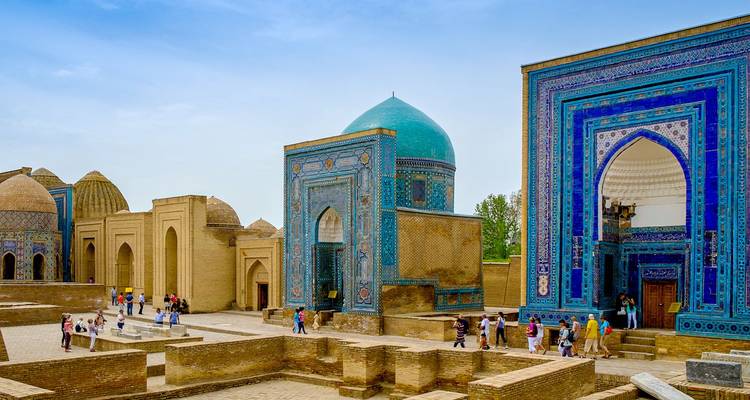 Blue-tiled mausoleums of Shah-i-Zinda in Samarkand with visitors exploring narrow stone lanes.