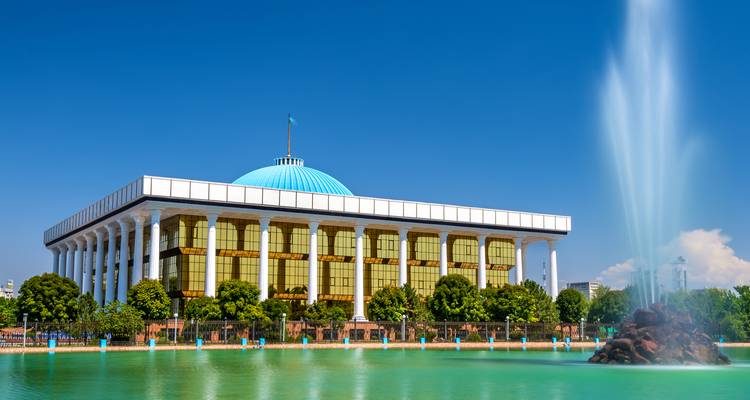 A grand building with white columns and a turquoise dome in an urban setting.