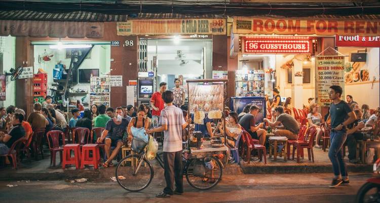 Animada escena de mercado callejero con gente y puestos de comida.