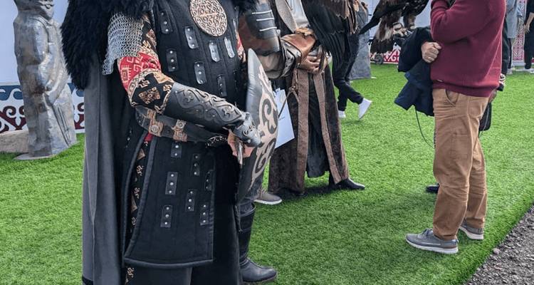 Personas con coloridos trajes tradicionales de guerreros kirguises en un evento cultural.