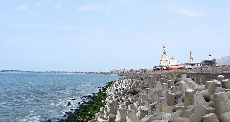 Paisaje costero con rompeolas y templo.