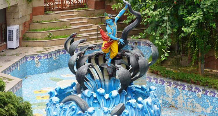 Estatua del Señor Krishna con serpientes en una fuente de agua decorativa.