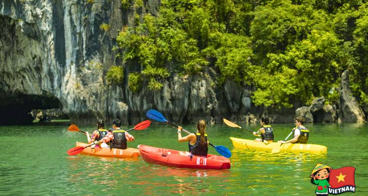 Mensen kajakken op smaragdgroene wateren met kalkstenen kliffen op de achtergrond.