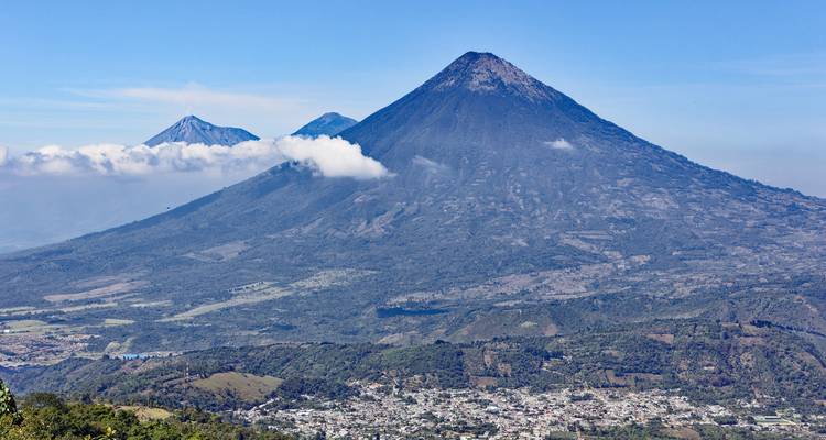 Majestätische Vulkanberge mit einem Dorf am Fuß unter einem klaren blauen Himmel.