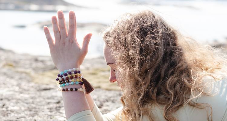 Mujer practicando yoga al aire libre junto al mar.