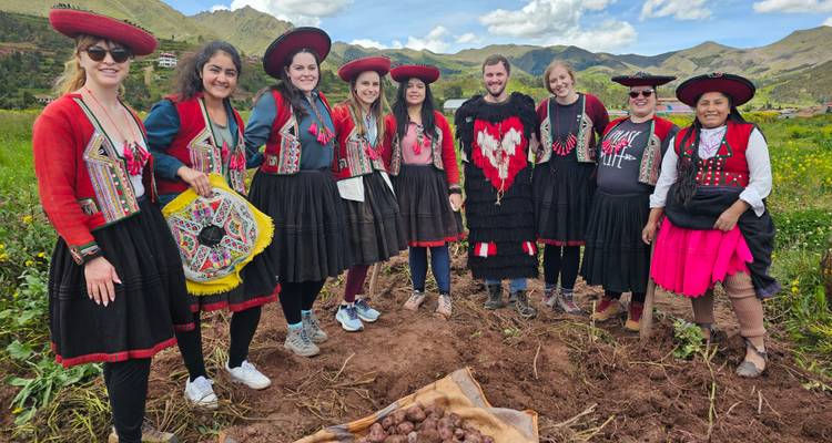 Grupo en ropa tradicional en un campo con papas.