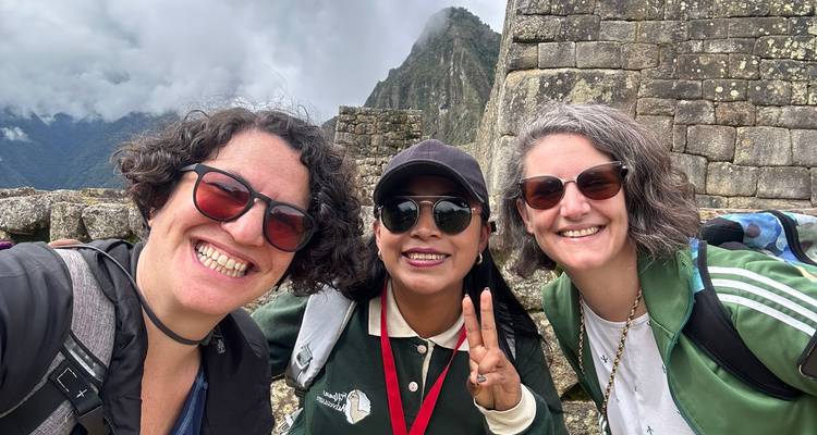 Grupo de amigos sonriendo con Machu Picchu de fondo.