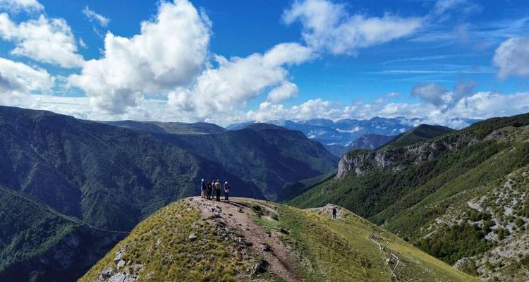 Grupo de excursionistas en el borde de una montaña con vistas panorámicas.