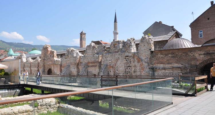 Personas caminando junto a ruinas antiguas en un entorno urbano.