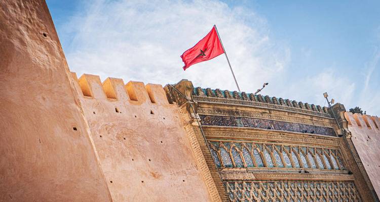 Bandera marroquí en una pared histórica con diseños intrincados.
