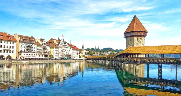 Le pont couvert en bois emblématique Chapel Bridge et la tour de l'eau se reflètent dans les eaux calmes de la rivière Reuss à Lucerne.