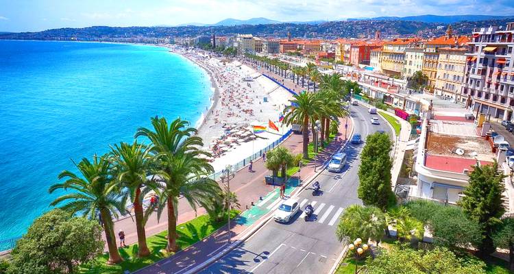 Une vue aérienne panoramique de la Promenade des Anglais de Nice, sa plage de sable, sa mer turquoise et son boulevard bordé de palmiers.