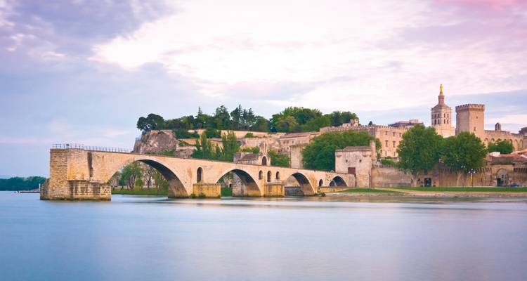 Pont Saint-Bénézet historique enjambant le Rhône avec les anciens remparts et le palais d'Avignon au crépuscule.